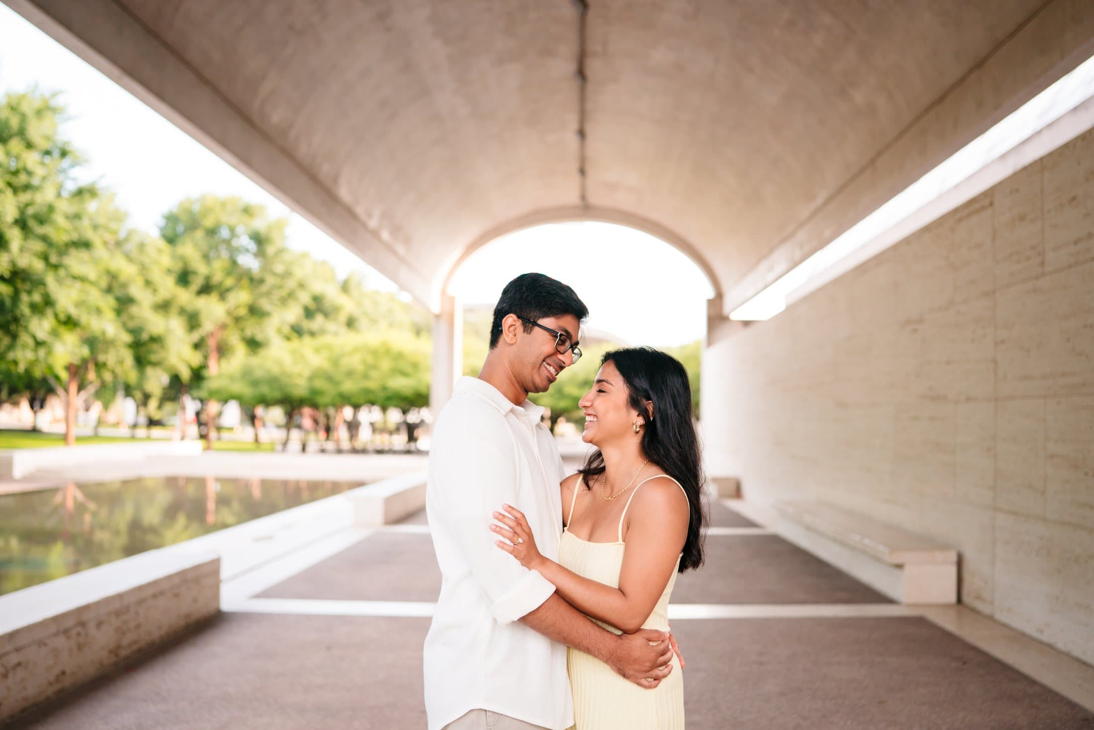 Riddhi and Rishabh laughing together beneath the vaulted pavilion at the Kimbell Art Museum